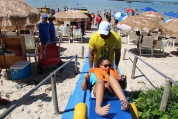 Por meio de cadeiras de roda especiais, projetadas para a praia, pessoas com deficiência participaram do banho de mar assistido
